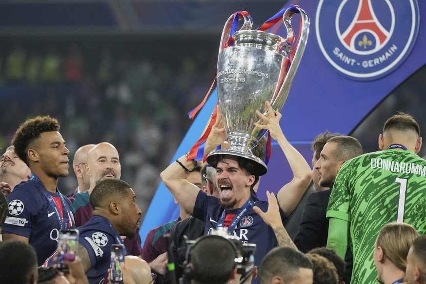 PSG's Vitinha celebrates with the trophy after winning the Champions League final soccer match between Paris Saint-Germain and Inter Milan at the Allianz Arena in Munich, Germany, Saturday, May 3 ...