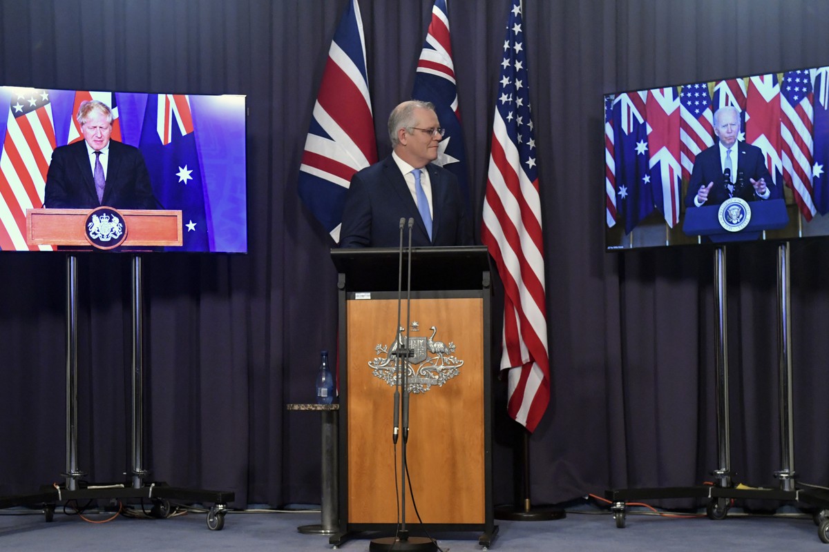 Australia's Prime Minister Scott Morrison, center, appears on stage with video links to Britain's Prime Minister Boris Johnson, left, and U.S. President Joe Biden at a joint press conference ...