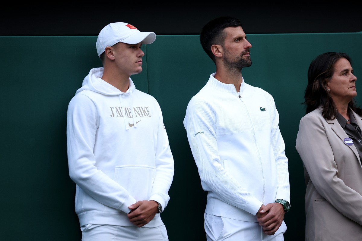 epa11457938 Novak Djokovic of Serbia (R) and Holger Rune of Denmark attend the post match interview of Andy Murray of Britain (unseen) after losing his Men's doubles 1st round match at the Wimble ...