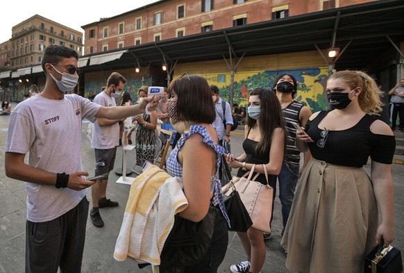 epa08525925 A worker wearing a face mask (L) checks the body temperatures of moviegoers to screen for possible infections with the SARS-CoV-2 coronavirus that causes the pandemic COVID-19 disease on t ...