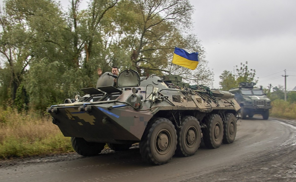 epa10188440 A Ukrainian serviceman waves from an armoured personnel carrier (APC) with the national flag near the urban settlement of Kazachya Lopan, north of Kharkiv, northeastern Ukraine, 16 Septemb ...