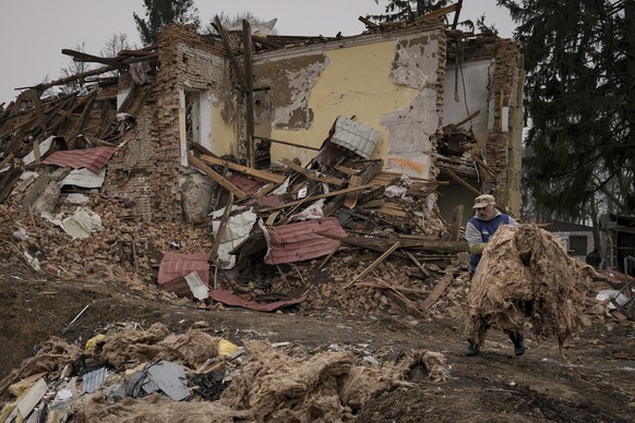 A man carries debris from buildings destroyed during fighting between Russian and Ukrainian forces outside Kyiv, Ukraine, Friday, April 1, 2022. Emergency relief and evacuation convoys for the besiege ...