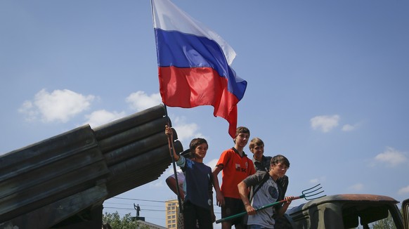 Kinder hissen eine russische Flagge.