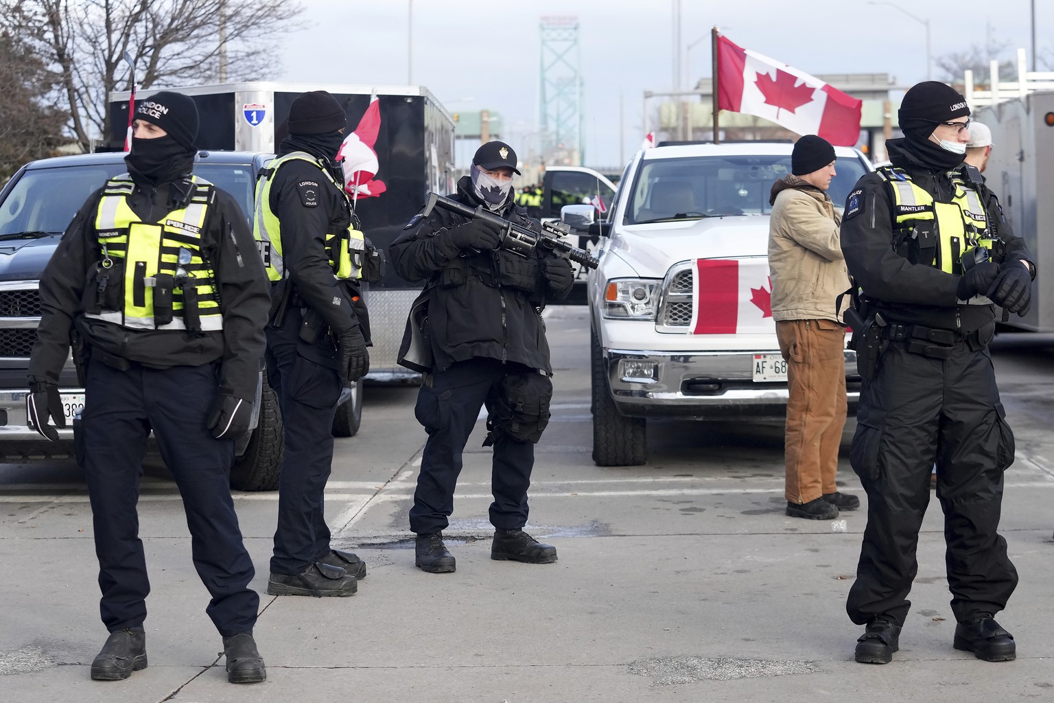 A police officer carries an ARWEN riot gun as officers prepare to enforce an injunction against a demonstration which has blocked traffic across the Ambassador Bridge by protesters against COVID-19 re ...