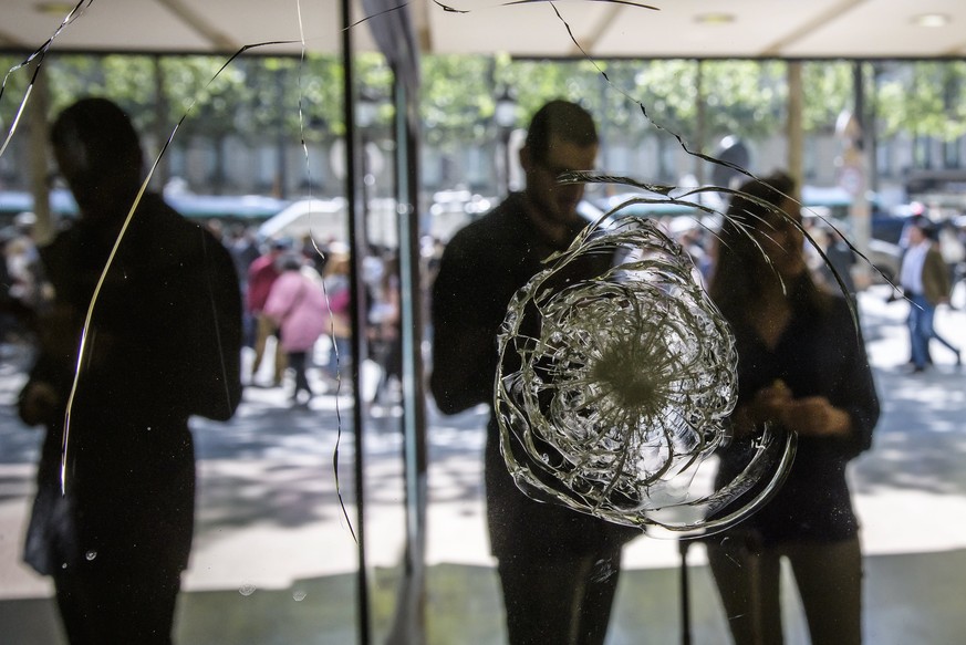 epa05919248 People watch bullet impacts on a windows at the 102 Champs Elysee avenue in Paris, France, 21 April 2017. A police officer the previous day was killed along with the attacker in a terror a ...