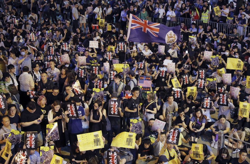 Pro-democracy protesters display placards and wave a colonial era flag of Hong Kong during a rally organized by higher education students in Chater Garden in Hong Kong, Friday, Aug. 16, 2019. China&#0 ...