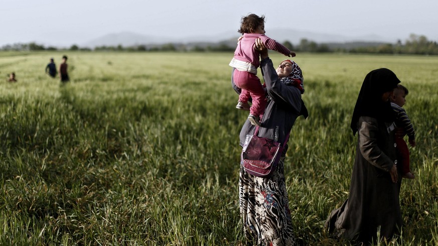 epa05259192 A Yezidi Kurdish refugee woman plays with her child at the refugee camp near the Greek-Macedonian border near Idomeni , Greece, 14 April 2016. Thousands of refugees remain stuck in Greece  ...