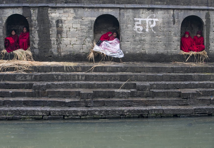 epa05149340 Nepalese Hindu women devotees are kept separate from other devotees due to menstruation, as others attend a mass worship ceremony as part of the Madhav Narayan festival at Bagmati river in ...