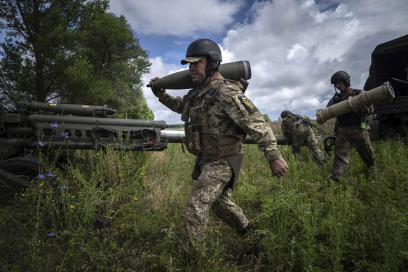 A Ukrainian serviceman carries a 155 mm artillery shell before firing at Russian positions from a U.S.- supplied M777 howitzer in Kharkiv region, Ukraine, Thursday, July 14, 2022. (AP Photo/Evgeniy Ma ...