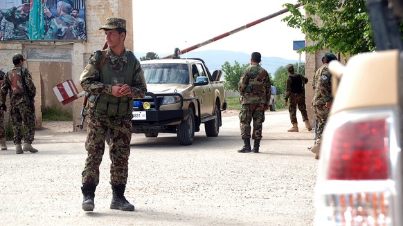 epa05920498 Afghan soldiers stand guard as military ambulances enter a military base a day after it was targeted by the militants in Balkh province, Afghanistan, 22 April 2017. Accoring to latest medi ...