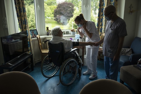 Nurse Jean-Claude Feda, right, and trainee Lyson Rousseau, center, both wearing face masks, to protect against the spread of coronavirus, measure the blood pressure of resident Odette Defraigne-Schmit ...