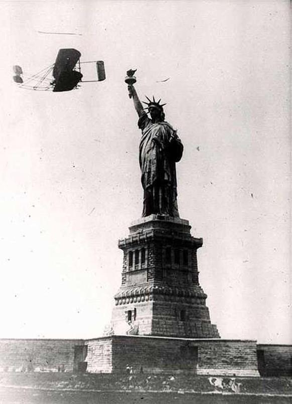 Wilbur Wright fliegt um die Freiheitsstatue. Er und sein Bruder waren amerikanische Flugzeugbauer, die zu Beginn des 20. Jahrhunderts die ersten Flüge mit Gleitflugzeugen und später gesteuerte Flüge m ...