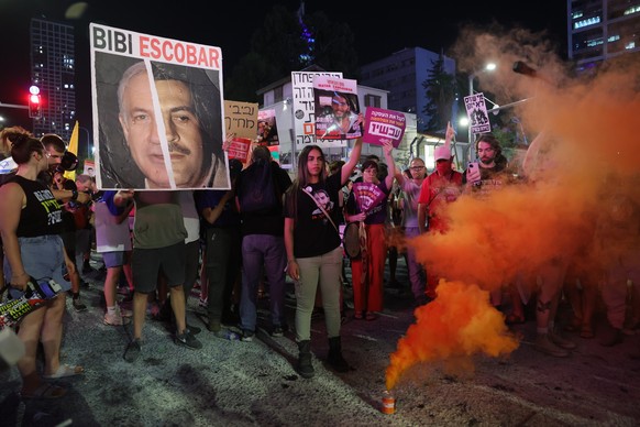 epa11413707 People light flares calling on the Israeli war cabinet to sign a hostage deal during a protest rally outside the Kirya military headquarters in Tel Aviv, Israel, 15 June 2024. According to ...