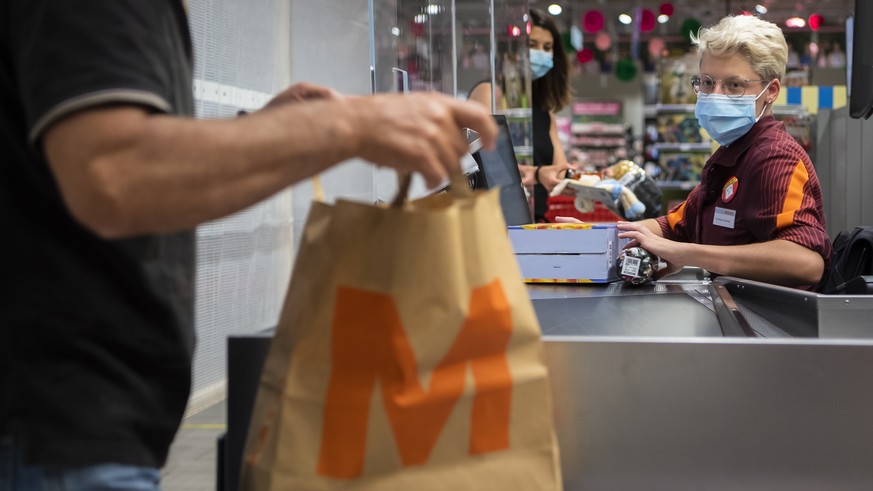 Une personne paie des courses a la caisse a une vendeuse portant un masque sur le visage dans un magasin Migros le mercredi 8 juillet 2020 a Crissier. Les masques sont obligatoires dans les magasins d ...