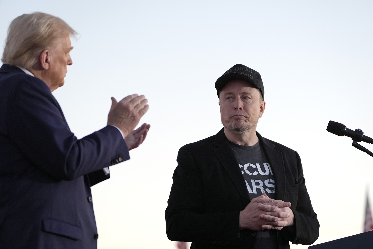 FILE - Republican presidential nominee former President Donald Trump, left, claps as Tesla and SpaceX CEO Elon Musk prepares to depart after speaking at a campaign event at the Butler Farm Show, on Oc ...