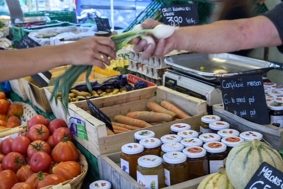 Un marchand de fruits et legumes vend des legumes et des fruits a une personne sur son stand au marche de detail et de produits manufactures de la Plaine de Plainpalais a Geneve, ce dimanche, 26. aout ...