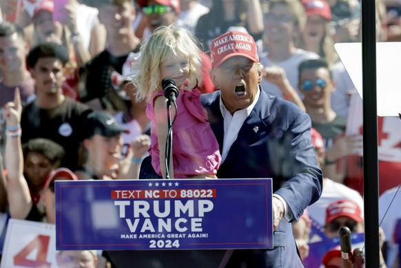 Republican presidential nominee former President Donald Trump holds his granddaughter Carolina Trump as he speaks at a campaign event at Wilmington International Airport in Wilmington, N.C., Saturday, ...