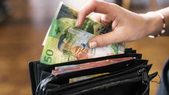 A waitress takes two fifty Swiss franc bills out of a her wallet, photographed in Zurich, Switzerland, on April 12, 2016. (KEYSTONE/Christian Beutler)

Eine Serviceangestellte entnimmt zwei Fuenfzig ...