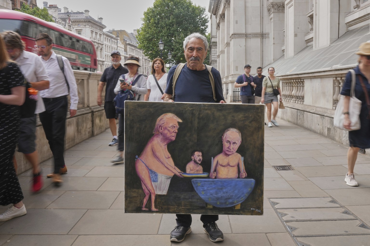 Satirical artist Kaya Mar, displays his latest painting depicting President Trump, Russian President Putin and Ukraine&#039;s President Zelenskyy, outside Downing Street, in London, Wednesday, Aug. 13 ...