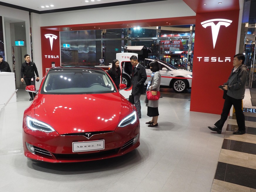 epa07228829 People look at a Tesla Model S electric car in a Tesla Store in Taipei, Taiwan, 13 December 2018. On 12 December, a Tesla Model S 2017 100D crashed into two parked police cars on a Taiwan  ...