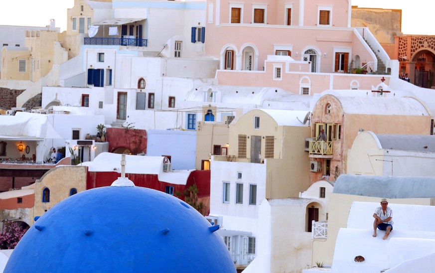 A man watches the sun set on the Greek island of Santorini, Greece, July 2, 2015. REUTERS/Cathal McNaughton/Files