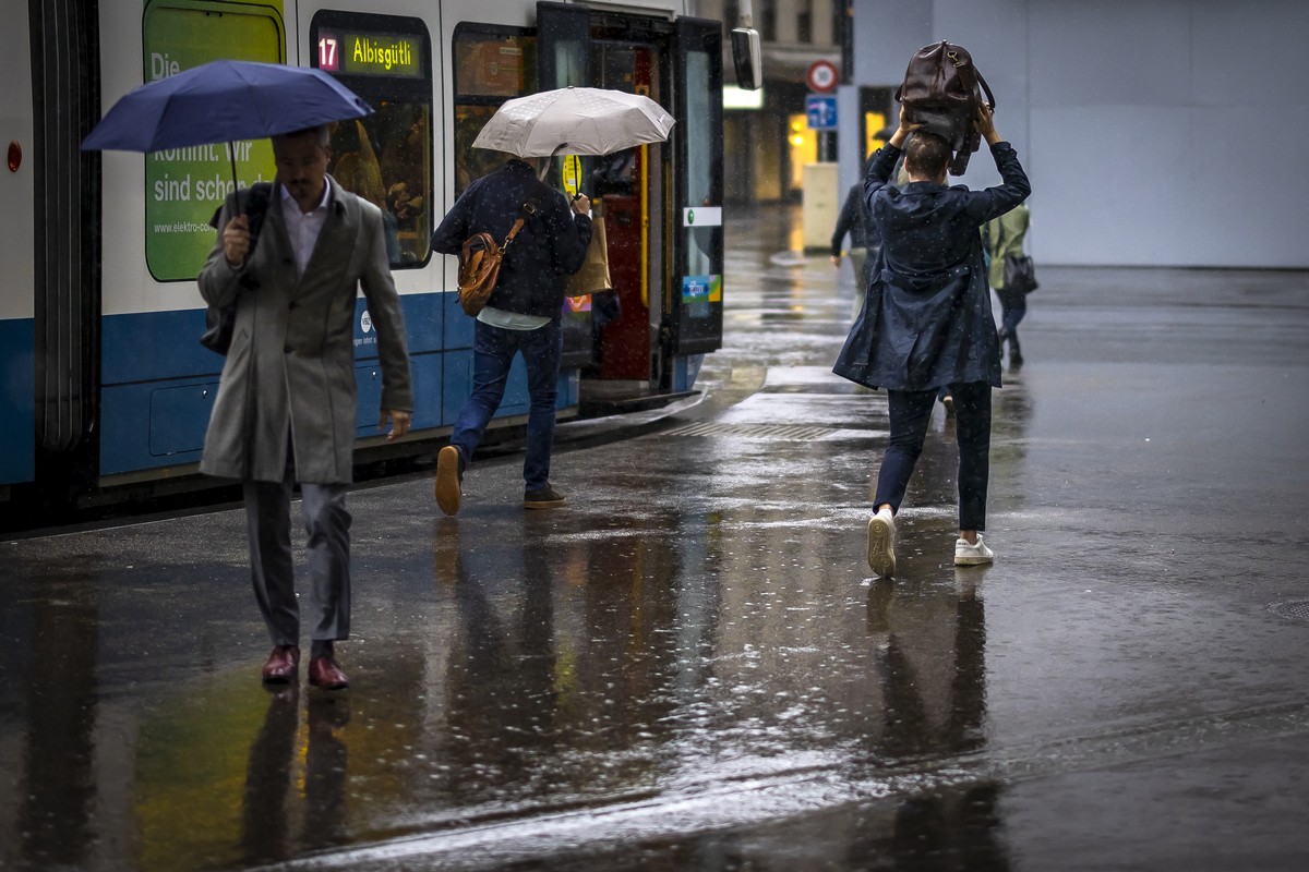 People hold umbrellas and bags to protect themselves from the rain as they cross the Paradeplatz on a rainy day, on Monday, June 3, 2024 in Zurich, Switzerland. (KEYSTONE/Michael Buholzer)