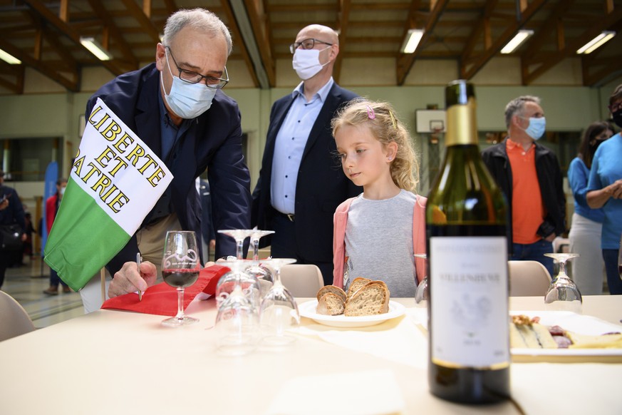 Le president de la Confederation Guy Parmelin, gauche, signe un autographe a une petite fille sur un drapeau Suisse lors d'un aperitif avec la population de la commune du Chenit pendant l'ex ...