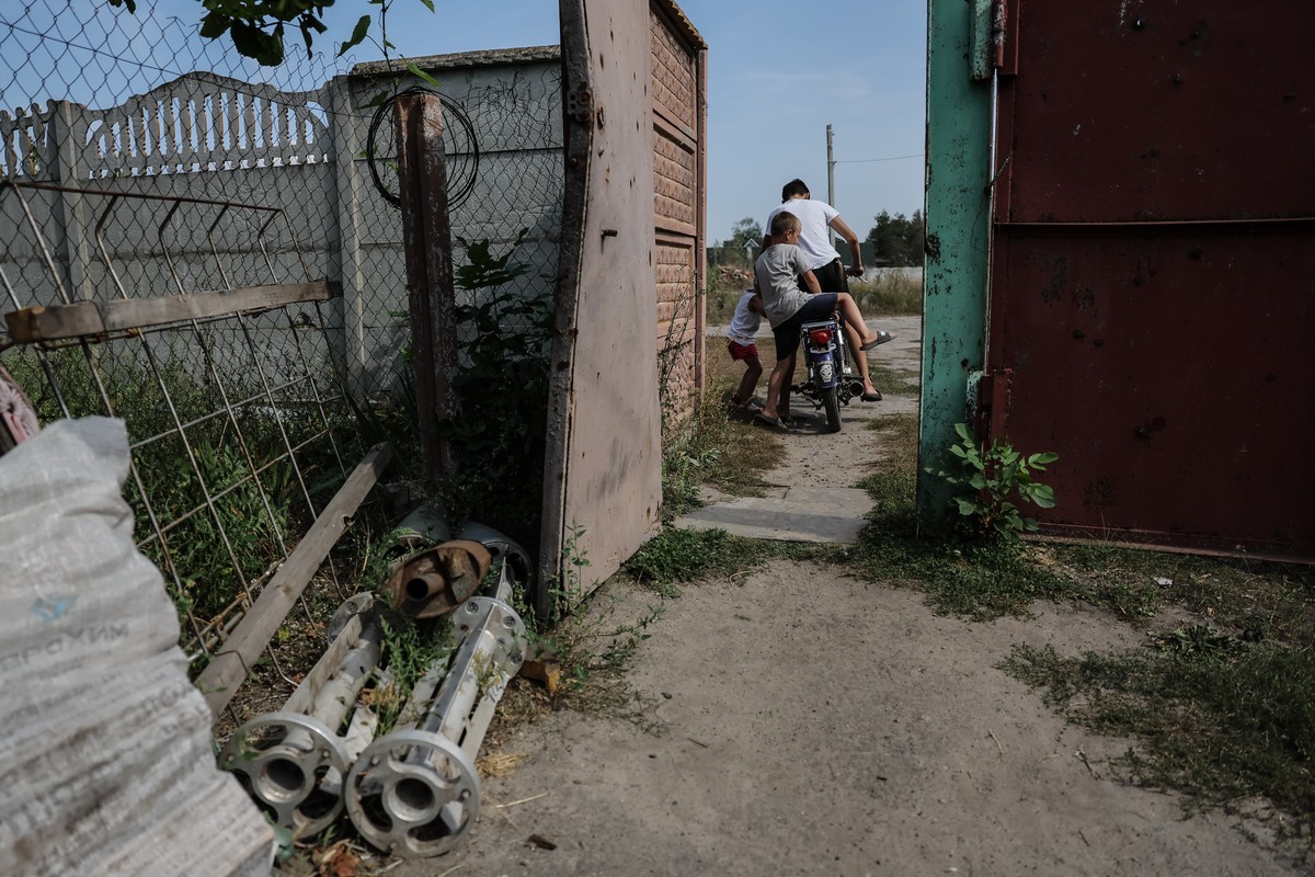 epa10833488 Children ride on the motorbike in the yard of their home which was damaged by Russian shelling and occupied by Russian soldiers in the village of Ruski Tyshky which is only 17 km's fr ...