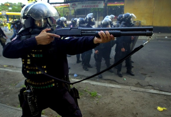 An anti-riot police officer lets off rubber bullets during a disturbance in which police used tear gas to disperse protesters who were attempting to enter a government building during a demonstration, ...
