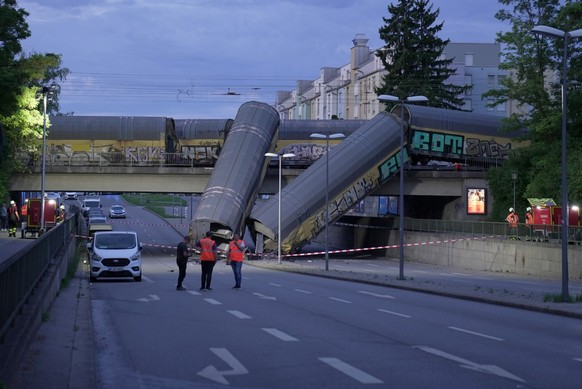 dpatopbilder - 20.06.2026, Bayern, M�nchen: Zwei Waggons eines G�terzugs liegen auf einer Stra�e, nachdem sie von einer Br�cke gest�rzt sind. Foto: Ehsan Monajati/dpa +++ dpa-Bildfunk +++ (KEYSTONE/DP ...