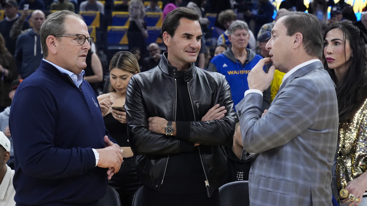 Former tennis player Roger Federer, center, talks to Golden State Warriors owner Joe Lacob, right, before the Warriors&#039; NBA basketball game against the San Antonio Spurs, Saturday, March 9, 2024, ...