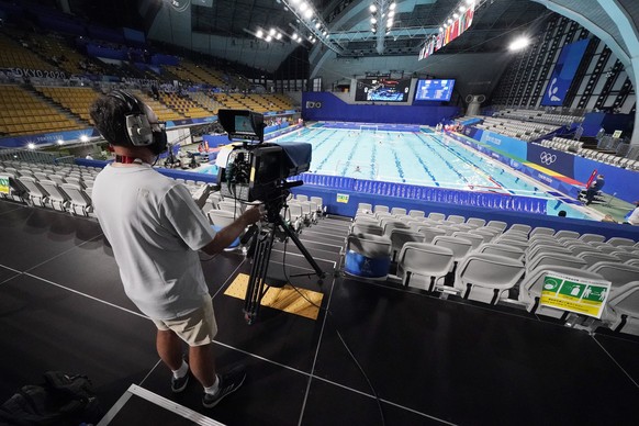 A camera operation works from behind empty seats in Tatsumi Water Polo Centre during a preliminary round men&#039;s water polo match at the 2020 Summer Olympics, Sunday, July 25, 2021, in Tokyo, Japan ...