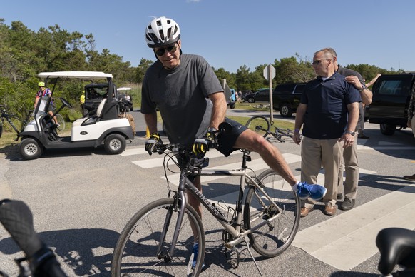 President Joe Biden gets back on his bike after he fell when he tried to get off his bike to greet a crowd at Gordons Pond in Rehoboth Beach, Del., Saturday, June 18, 2022. (AP Photo/Manuel Balce Cene ...