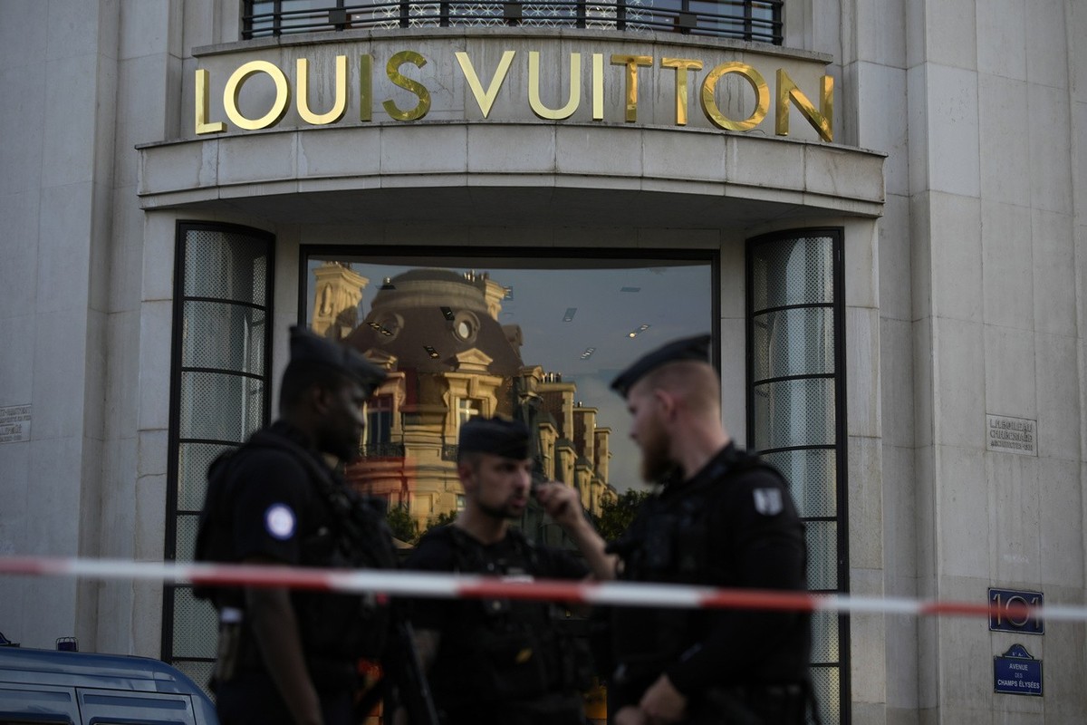 Police officers stand guard at the Louis Vuitton store on the Champs-Elysees avenue, after a stabbing Thursday, July 18, 2024 in Paris. French Interior Minister Gerald Darmanin said a police officer w ...