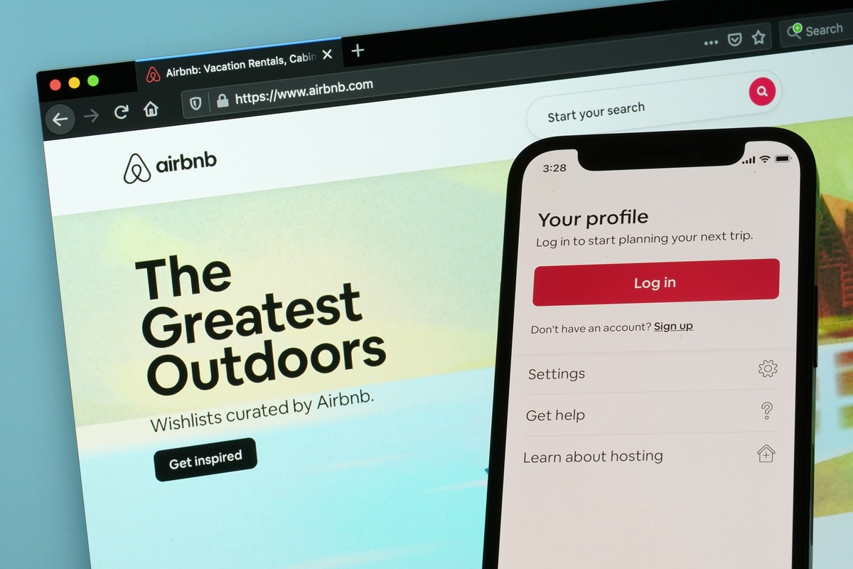 The login page for Airbnb's iPhone app is seen in front of a computer displaying Airbnb's website, Saturday, May 8, 2021, in Washington. Airbnb says it's taking steps to prevent people  ...