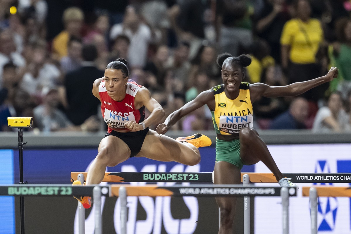 Ditaji Kambundji of Switzerland, left, and Ackera Nugent of Jamaica clear a hurdle during the women's 100 meters hurdles final at the World Athletics Championships at the National Athletics Centr ...