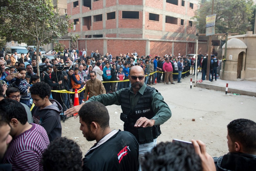 epa06409044 A security official keeps people outside a cordoned off area at the scene of attack on Mar Mina church in the district of Helwan, southeastern Cairo, Egypt, 29 December 2017. At least five ...