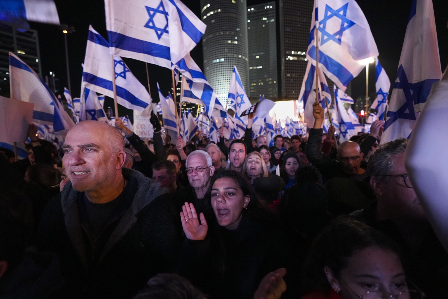 Israelis wave the national flag during a protest against plans by Prime Minister Benjamin Netanyahu&#039;s new government to overhaul the judicial system, in Tel Aviv, Israel, Saturday, Feb. 18, 2023. ...