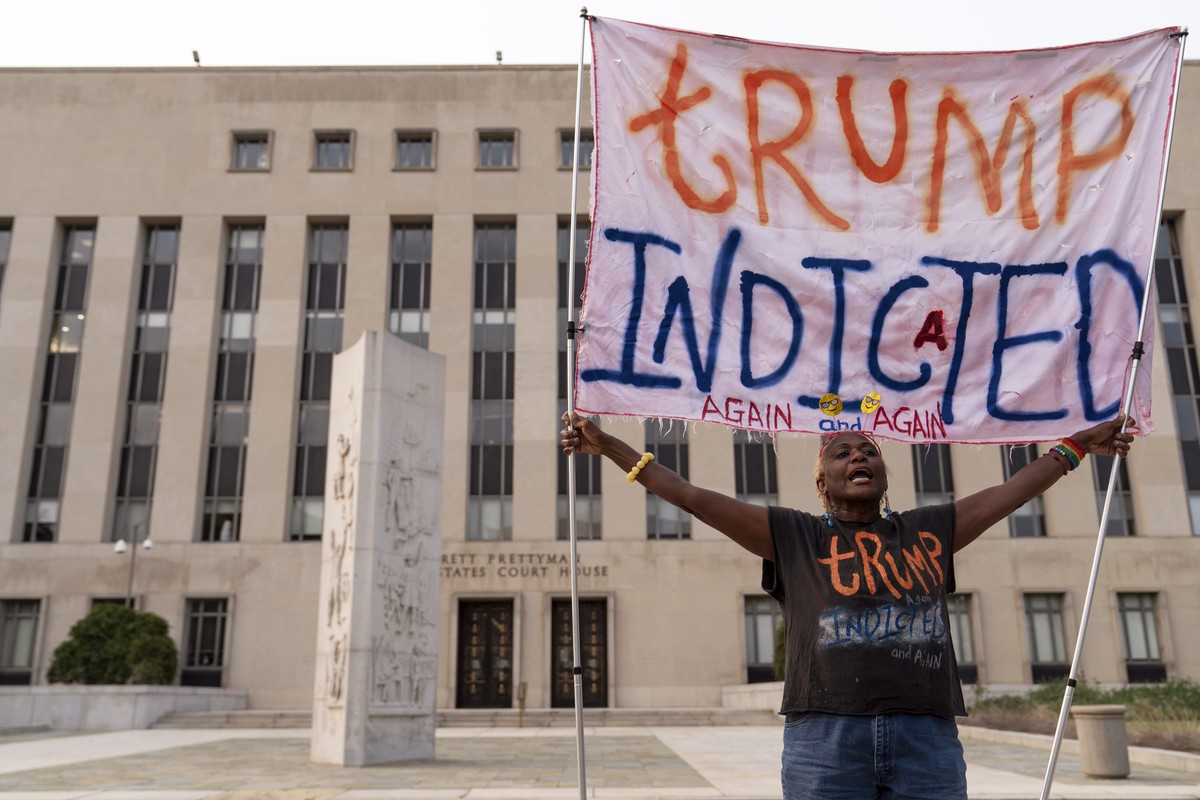 Nadine Seiler protest as she holds a banner outside federal court Tuesday, Aug. 1, 2023 in Washington. Former President Donald Trump has been charged by the Justice Department for his efforts to overt ...