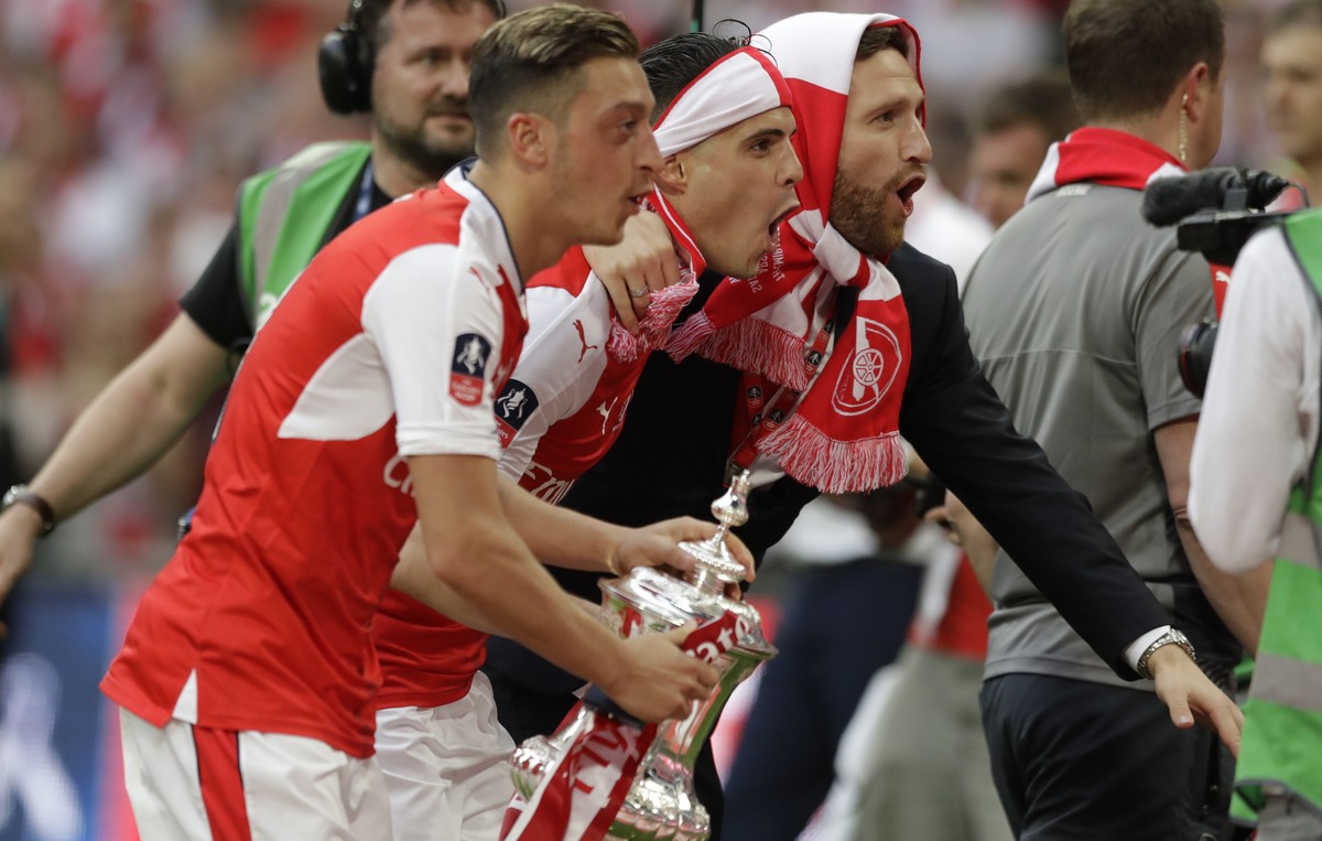 From left, Arsenal's Mesut Ozil, Granit Xhaka and Shkodran Mustafi celebrate with the trophy after winning the English FA Cup final soccer match between Arsenal and Chelsea at the Wembley stadium ...