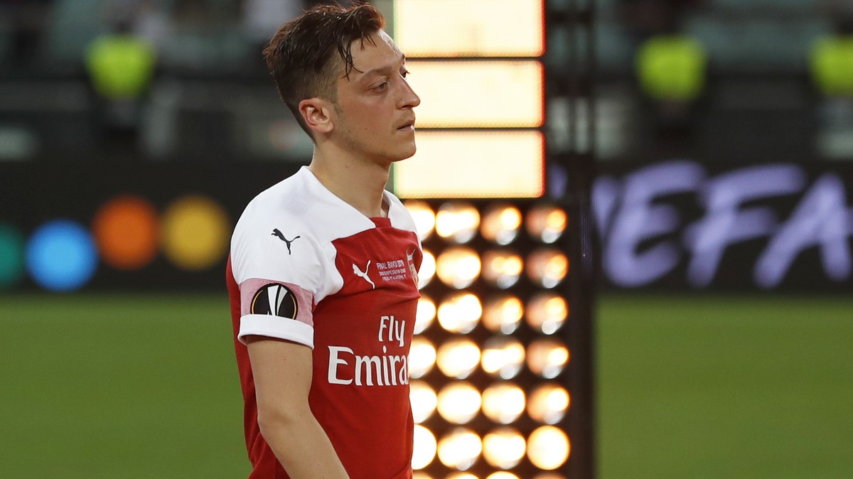 Arsenal's Mesut Ozil walks past the trophy after receiving his second place medal after the Europa League Final soccer match between Chelsea and Arsenal at the Olympic stadium in Baku, Azerbaijan ...