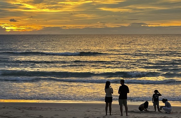 FILE - Tourists stand on Bang Tao Beach in Phuket, southern Thailand on Oct. 22, 2021. Thai authorities say that on July 1, 2022, they are lifting the need for arriving foreign visitors to register on ...