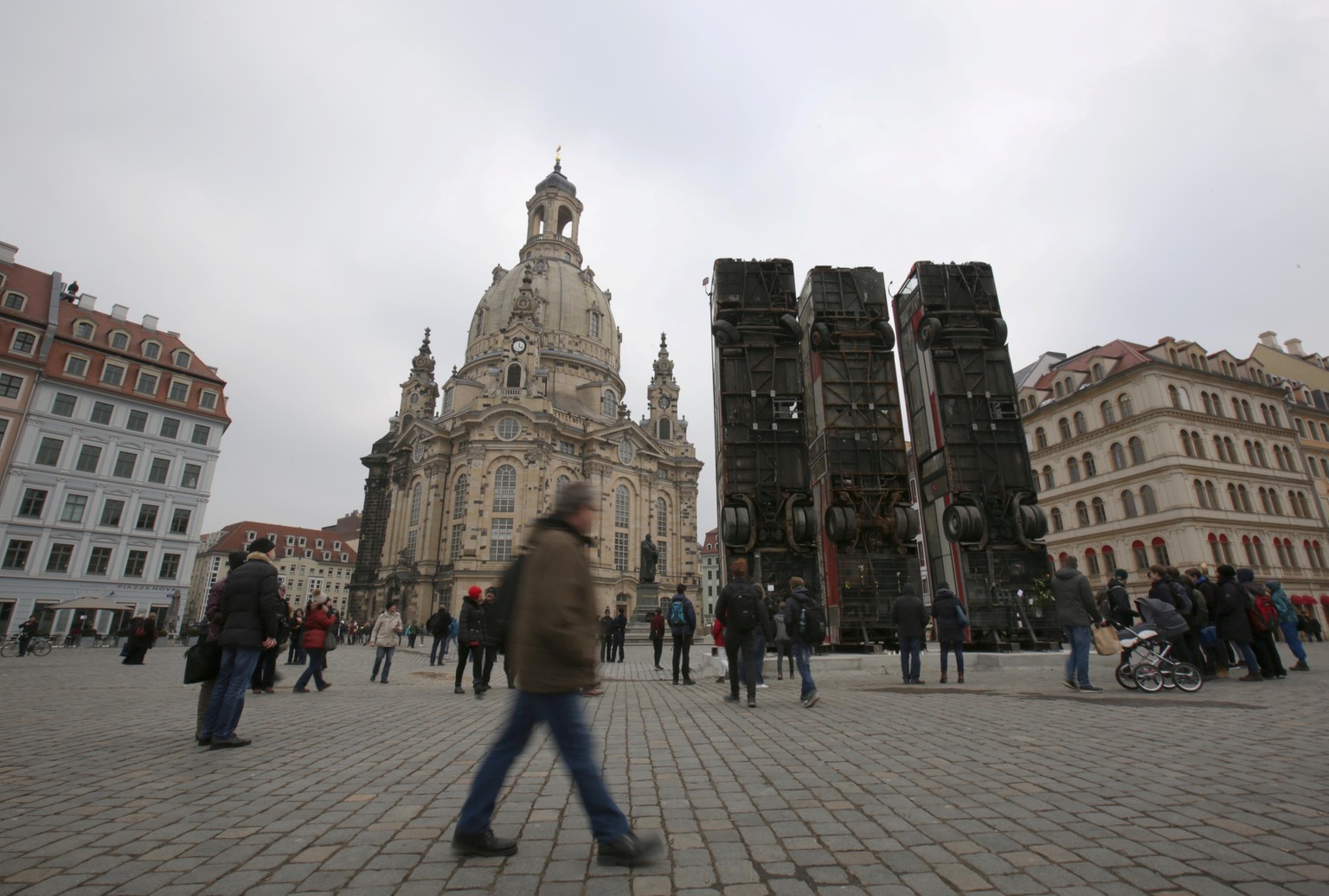 People walk next to the art instalation &quot;Monument&quot; by Syrian artist Manaf Halbouni, made from three passenger busses in Dresden, Germany February 8, 2017. REUTERS/Matthias Schumann