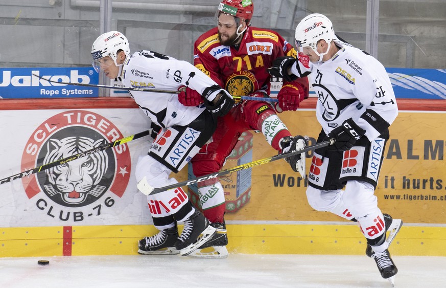 Tigers Julian Schmutz, Mitte, kaempft um den Puck gegen Luganos Reto Suri, links, und Alessandro Chiesa, rechts, waehrend dem Meisterschaftsspiel der National League zwischen den SCL Tigers und dem HC ...