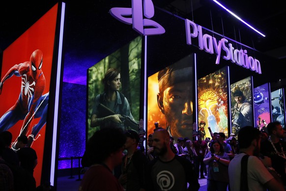 FILE - In this June 14, 2018 file photo people stand on a line next to the PlayStation booth at the Los Angeles Convention Center. PlayStation-maker Sony is escalating its competition with Xbox-maker  ...
