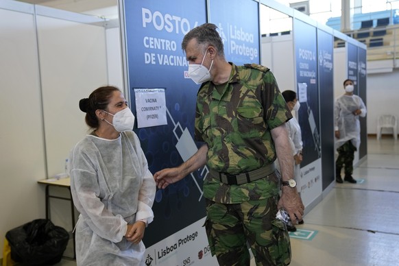 Rear Admiral Henrique Gouveia e Melo shares a joke with a military nurse during a visit to a vaccination center in Lisbon, Tuesday, Sept. 21, 2021. As Portugal nears its goal of fully vaccinating 85%  ...
