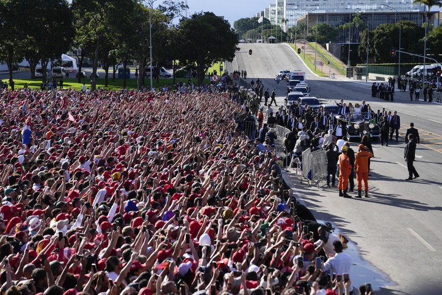 Supporters wave as Luiz Inacio Lula da Silva arrives on an open car to the Planalto Palace after he was sworn in as new president in Brasilia, Brazil, Sunday, Jan. 1, 2023. (AP Photo/Silvia Izquierdo)