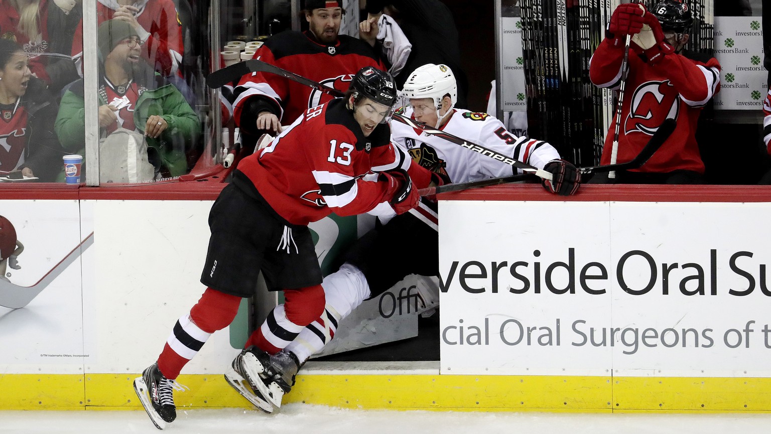 Chicago Blackhawks defenseman Connor Murphy (5) gets checked into the New Jersey Devils bench by center Nico Hischier (13), of Switzerland, during the third period of an NHL hockey game, Monday, Jan.  ...