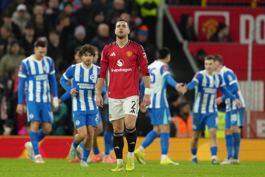 Manchester United's Diogo Dalot walks to the center as Brighton players celebrate a goal during the FA Cup third round soccer match between Manchester United and Brighton in Manchester, England,  ...