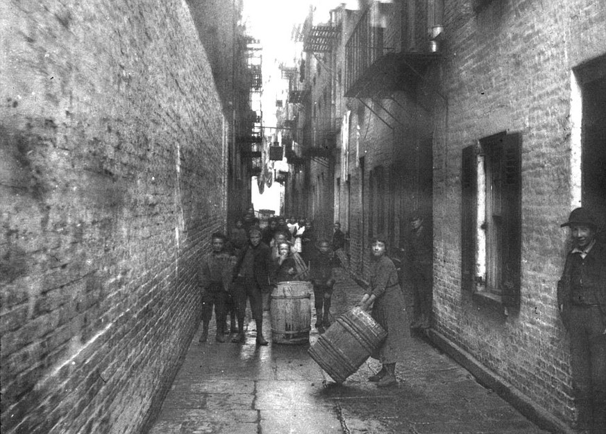 Kinder spielen mit Fässern auf einer Strasse in New York, um 1890.